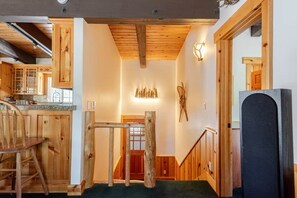 Un interior de madera con una escalera, un comedor con mesa y sillas de madera, y una zona de cocina con armarios y encimera.