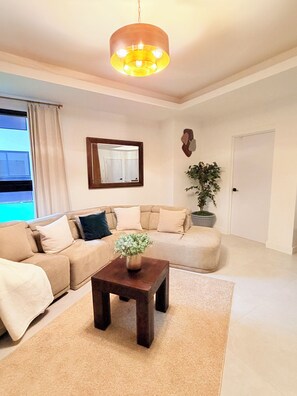 A living room with a sofa, a coffee table, a mirror, and a potted plant. - Spacious 2 bedroom apartment in charming Kingston with pool. (Kingston)