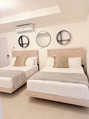 A hotel room with two beds, a ceiling fan, and three wall-mounted mirrors. - Spacious 2 bedroom apartment in charming Kingston with pool. (Kingston)