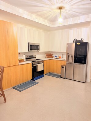 A modern kitchen with white cabinets, a stainless steel refrigerator, a microwave, and a built-in oven. - Spacious 2 bedroom apartment in charming Kingston with pool. (Kingston)