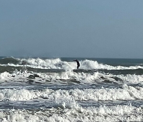 A beach with waves and a person surfing. - Coastal three-bedroom condo near the beach, pool and park (Corpus Christi)
