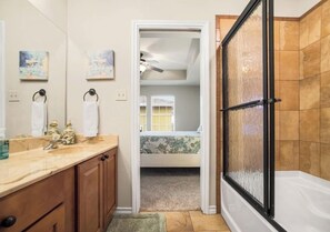 A bathroom with a shower, a sink, and a mirror. There is a door leading to a bedroom with a bed and a window. - Coastal three-bedroom condo near the beach, pool and park (Corpus Christi)