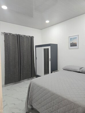 Um quarto com cama, cortinas, guarda-roupa, um quadro na parede e uma luminária no teto.