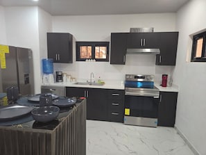 A compact kitchen with a built-in oven, a water dispenser, and a coffee maker.