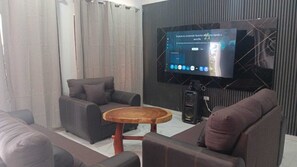 A modern living room with a sofa, armchair, and coffee table, a television, and a sound system.