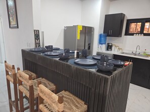 Une cuisine dotĂ©e dâun Ăźlot central, dâappareils Ă©lectromĂ©nagers en acier inoxydable et dâun meuble noir.