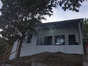 Um edifício moderno com fachada branca, grandes janelas e guarda-corpo metálico.