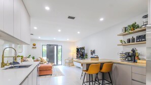 Une cuisine moderne dotée d’un îlot central, de tabourets de bar et d’un coin café.