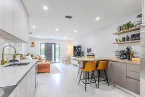 Una cocina moderna con una isla central, taburetes de bar y una estación de café.
