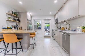 Una cocina moderna con una isla central, taburetes de bar y electrodomésticos integrados.