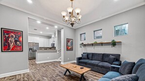 Ein modernes Wohnzimmer mit einem grauen Sofa, einem Holztisch und einer Kristallleuchtre.