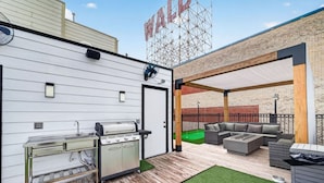 Eine Außenpatio mit Grill, Sitzbereich und einem Gebäude mit einem 'WALD'-Schild.
