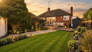 A house with a well-maintained lawn, a patio with outdoor furniture, and a small shed.