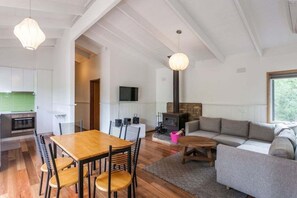 A modern living space with a dining area, a sofa, a fireplace, and a television. - Aireys Inlet Beach House (Aireys Inlet)