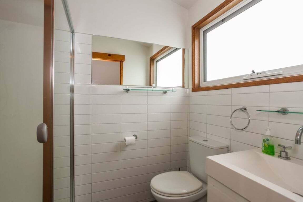 A small bathroom with a toilet, a sink, a mirror, and a window.