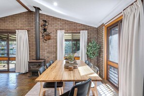 Ein Essbereich mit Backsteinwand, Kaminofen, langem Tisch und Stühlen.