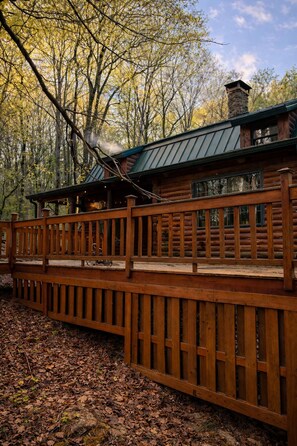 A log cabin with a wooden deck and a metal roof.