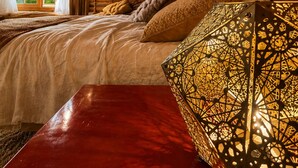 Un dormitorio de cabaña de madera con una cama, un banco rojo y una lámpara decorativa.