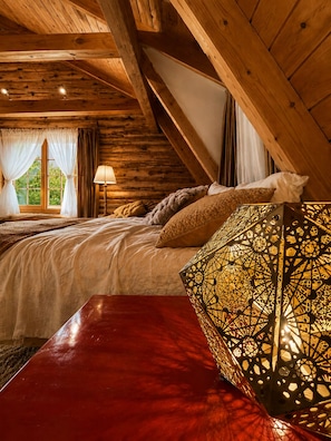 Ein Schlafzimmer in einer Holzhütte mit einem Bett, einer roten Bank und einer dekorativen Lampe.