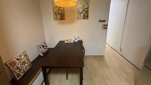 A dining area with a table, chairs, a hanging lamp, and two wall-mounted flower paintings. - GORO HOTEL (Tokyo)