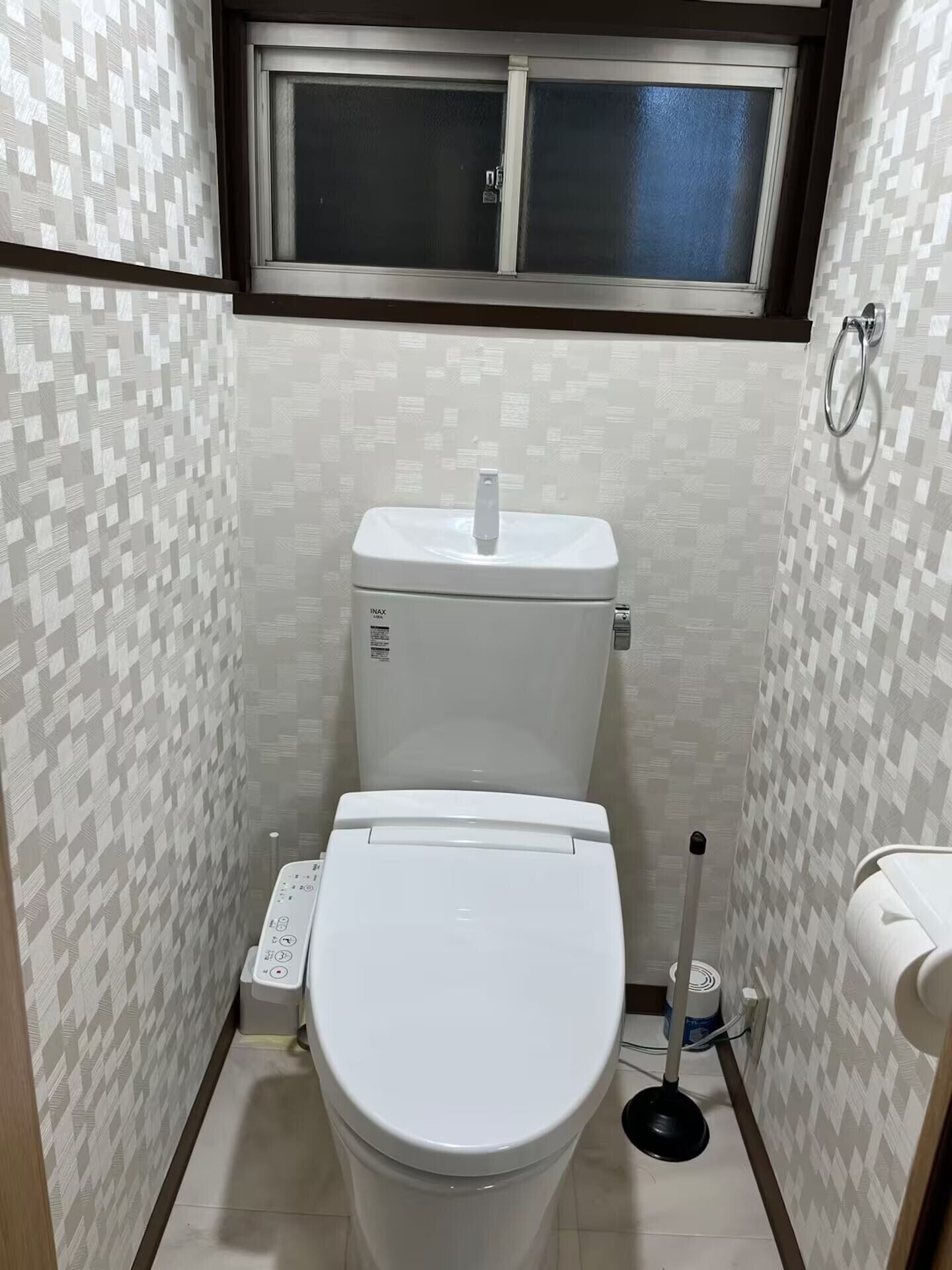 A small bathroom with a toilet, bidet, and a window above the toilet.