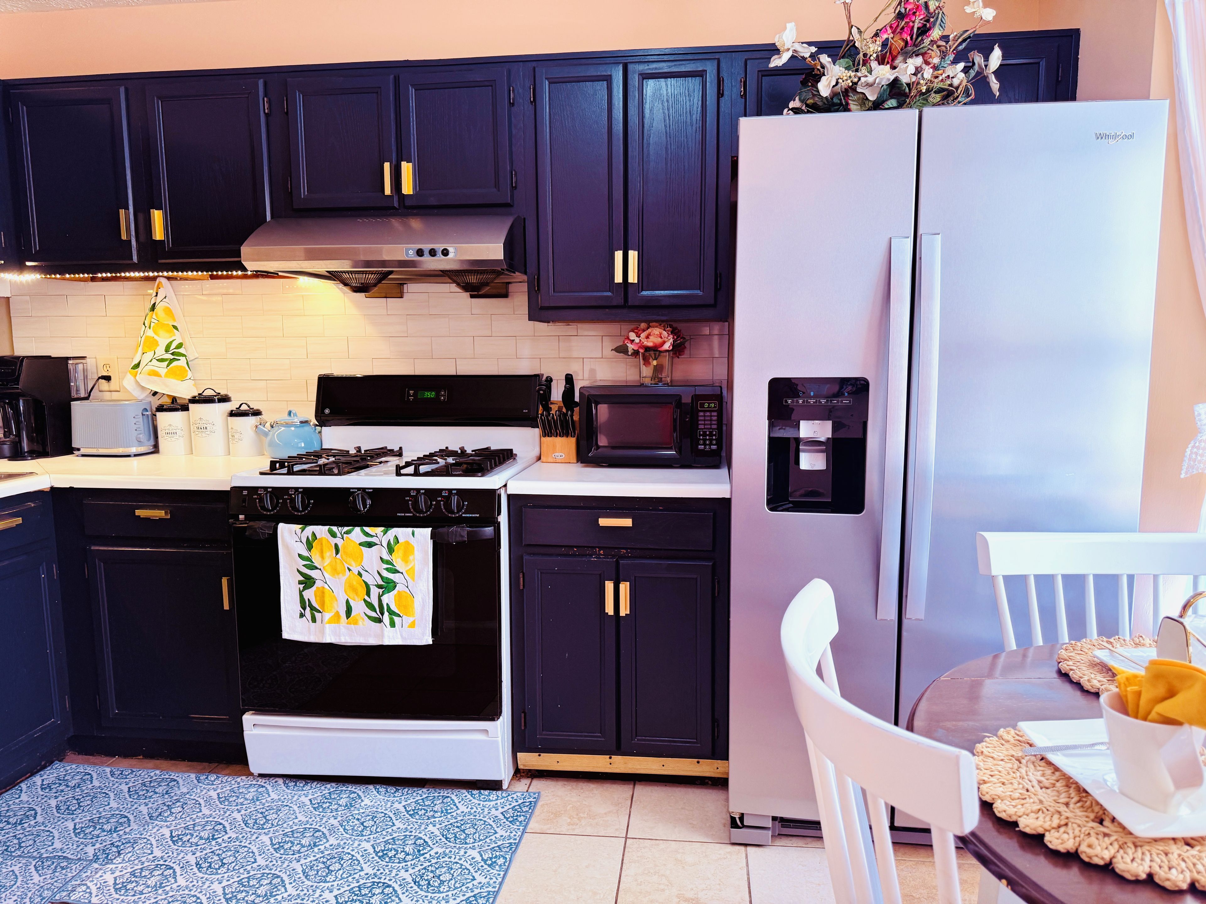 A modern kitchen with dark cabinetry, a stainless steel refrigerator, a stove, and a microwave.