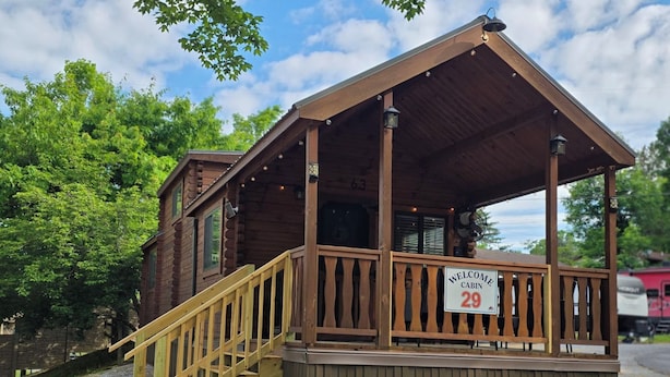 A cabin with a wooden exterior, a covered porch, and a staircase leading to the entrance. - Family Cabin w/ Loft | Arcade | Pigeon Forge (Pigeon Forge)