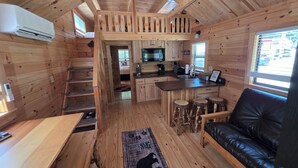 A cabin interior with a kitchen, dining area, and a living room with a black leather sofa. - Family Cabin w/ Loft | Arcade | Pigeon Forge (Pigeon Forge)