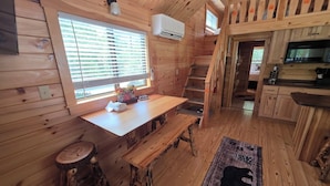 A wooden cabin interior with a dining area, kitchen, and a staircase. - Family Cabin w/ Loft | Arcade | Pigeon Forge (Pigeon Forge)