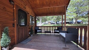 A covered patio with wooden walls, numbered 63, featuring outdoor seating and a small potted plant. - Family Cabin w/ Loft | Arcade | Pigeon Forge (Pigeon Forge)