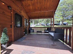 Un patio techado con paredes de madera, número 63, con mobiliario exterior y una pequeña planta en maceta.