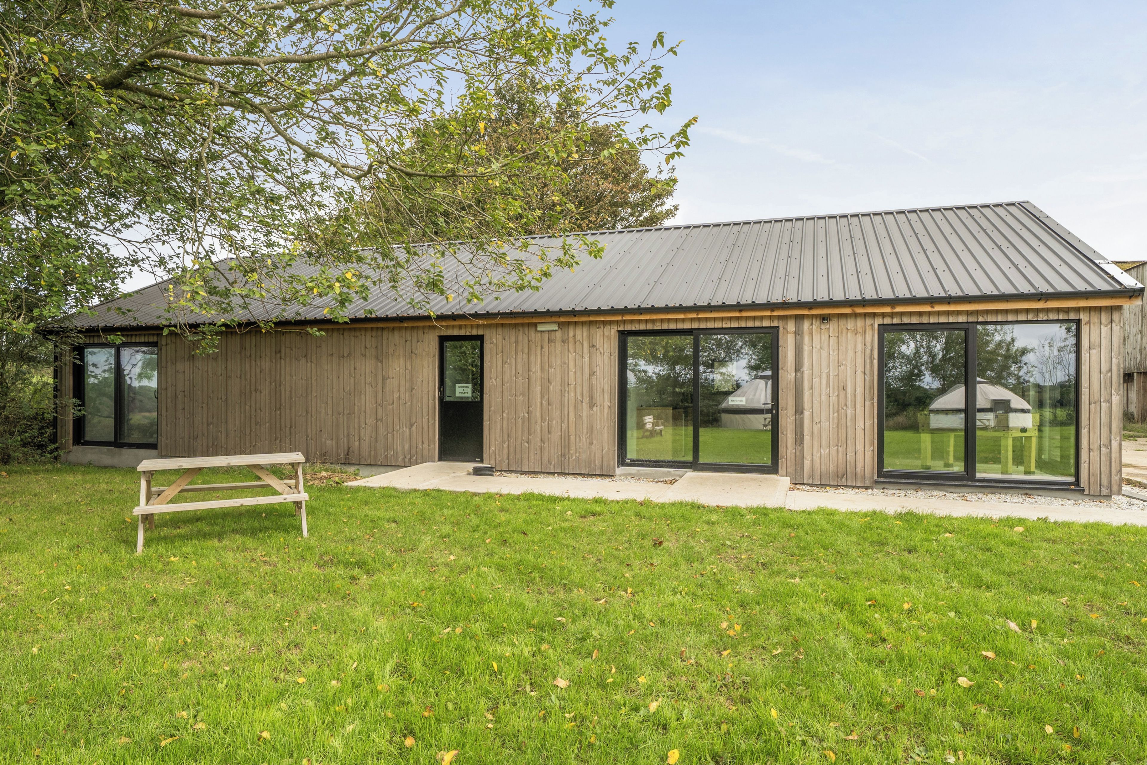 A modern wooden building with large windows and a metal roof.