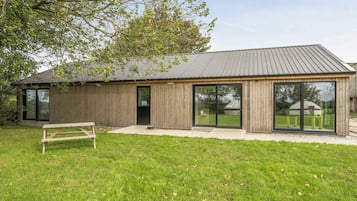 A modern wooden building with large windows and a metal roof.