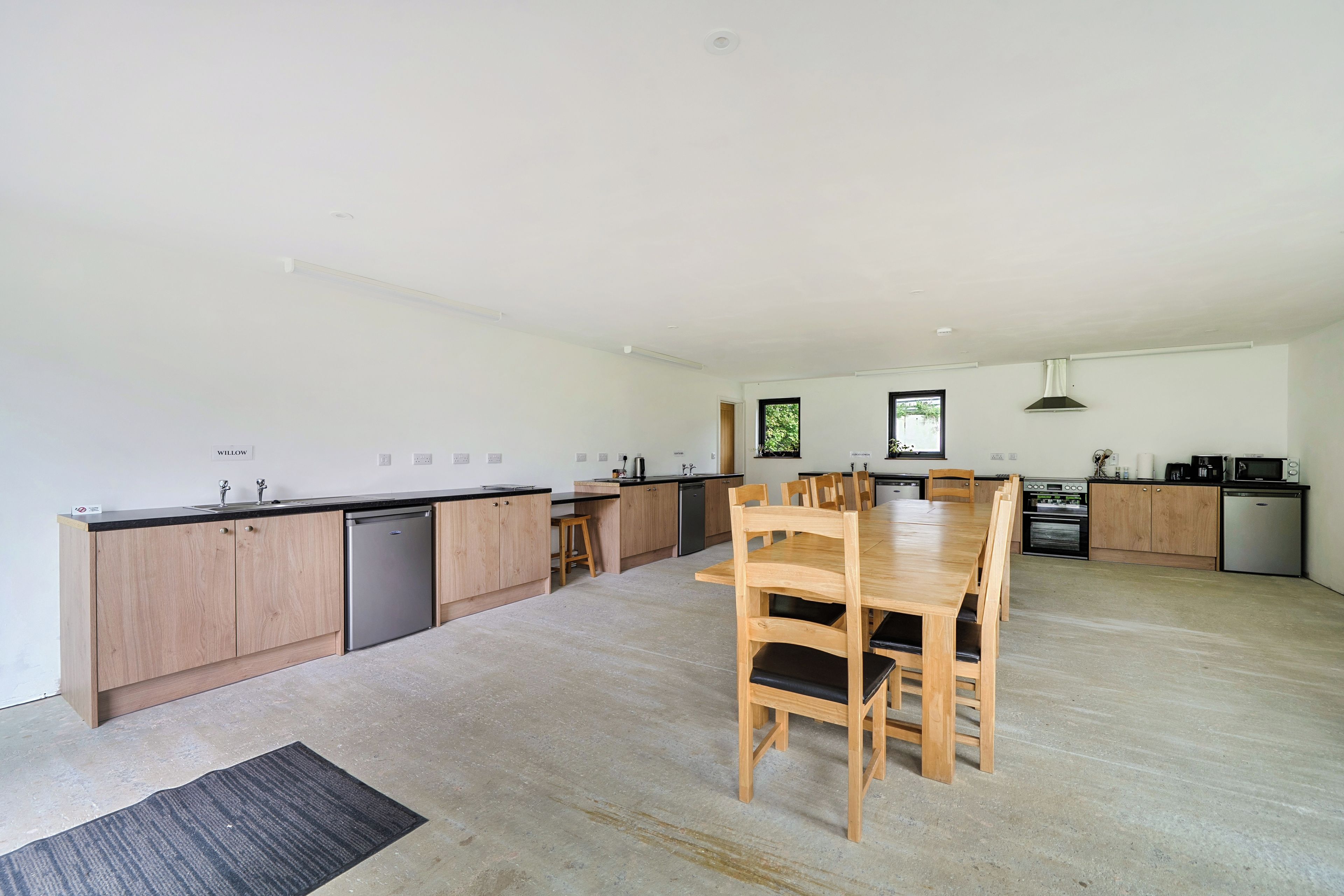 A modern kitchen with wooden cabinets, a central island, and a dining table with chairs.