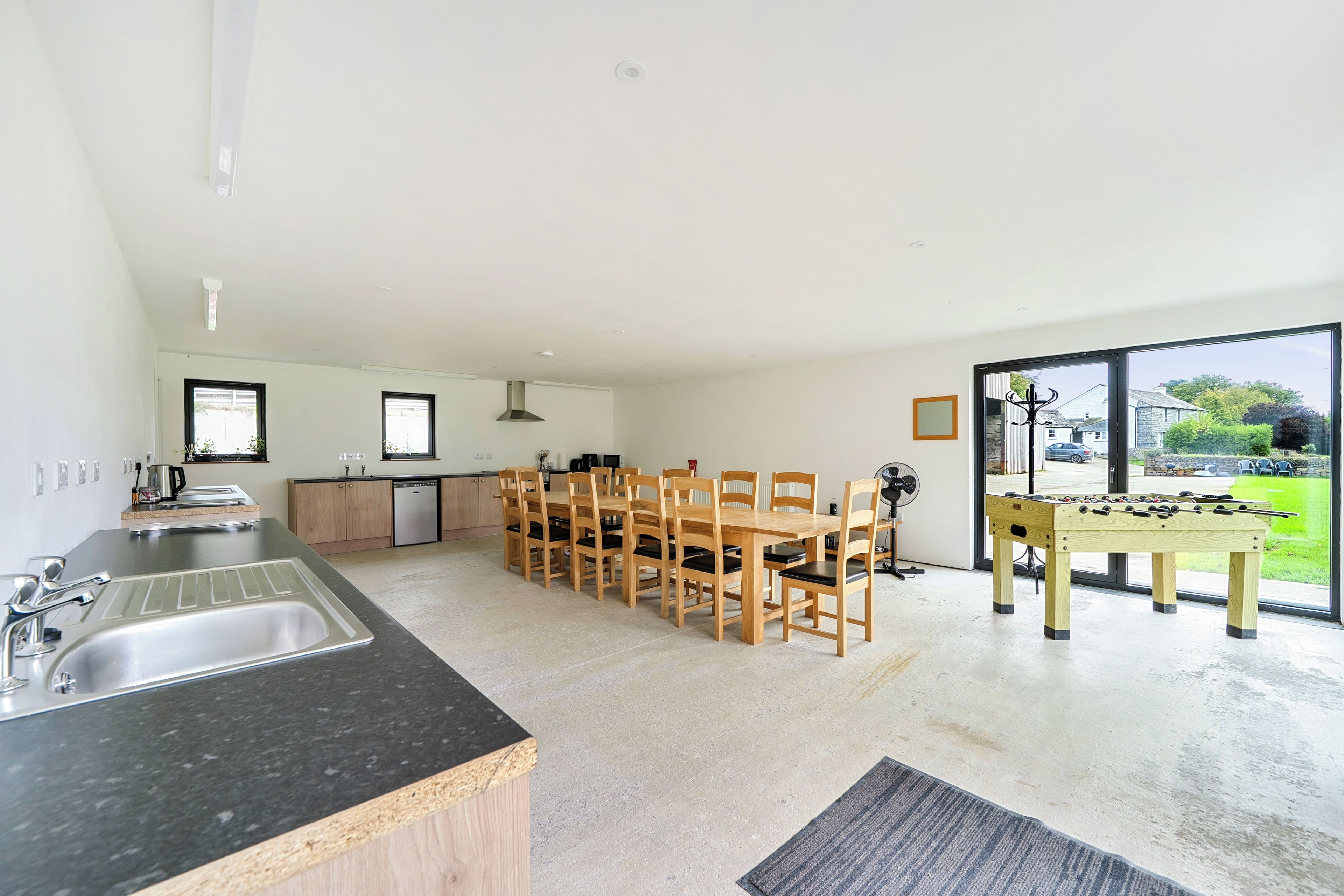 A modern kitchen with a dining area, a foosball table, and a view of the outdoors.