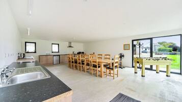 A modern kitchen with a dining area, a foosball table, and a view of the outdoors.