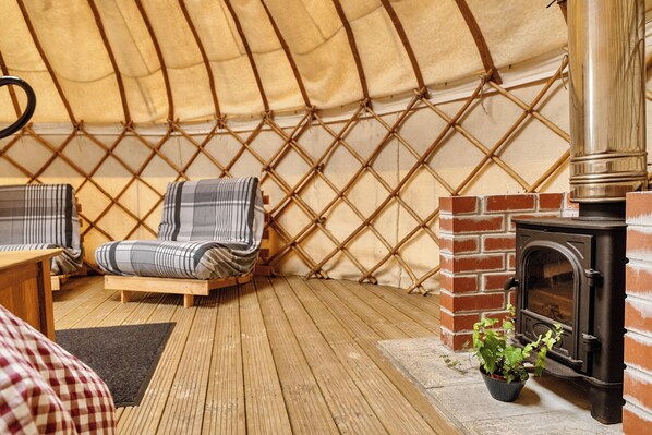 Un interior acogedor con suelo de madera, un sillón escocés, una mesita y una chimenea de ladrillo.