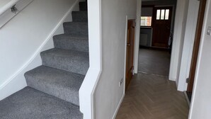 A staircase with carpeted steps leading to a landing, a wooden floor, and a door leading to another room. - Ayr 2-Bed House, Sleeps 4 with Garden & Parking (Ayr)