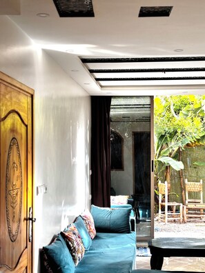 A modern interior with a blue sofa, wooden door, and a view of a garden. - Garden view Double Room• 3Min walk to Banana Beach Tamraght . (Tamraght)