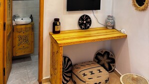 A bathroom with a wooden vanity, a television mounted on the wall, and a decorative ceiling light.
