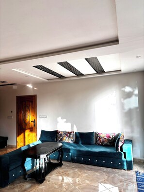 Ein Wohnzimmer mit einem blauen Sofa, einem Couchtisch und einer Holztür.