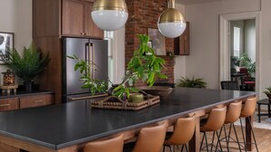 Una cocina moderna con una isla central, armarios de madera y una pared de ladrillo decorativa.