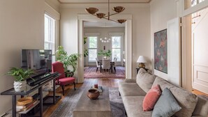 Una sala de estar con televisión, sofá, mesa de centro y un comedor con sillas y una mesa.