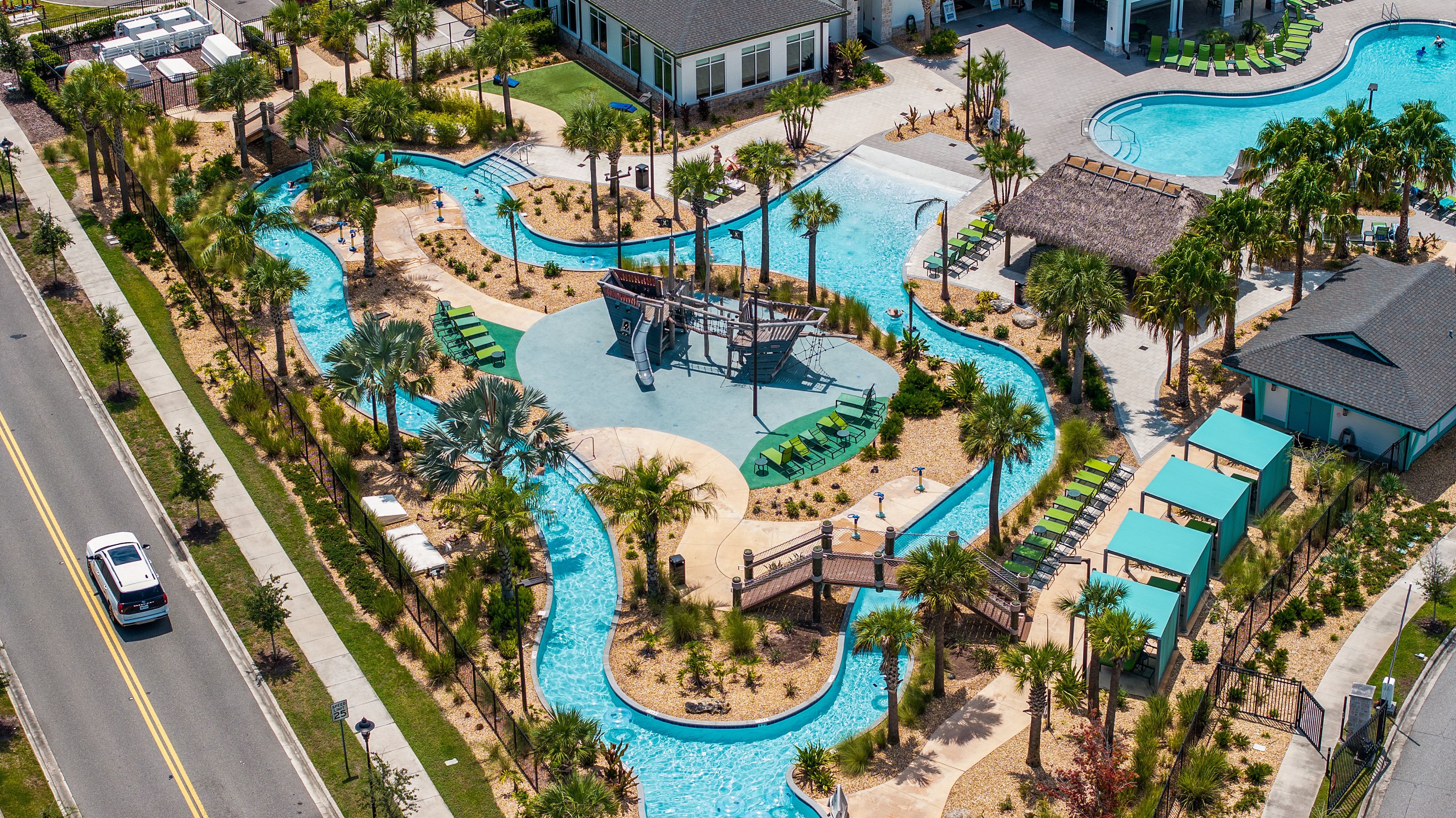 An aerial view of a resort with multiple swimming pools, palm trees, and lounge areas.