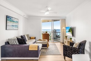 A modern living room with a sofa, armchair, and a television. - Chevron Renaissance Ocean & River Views (Surfers Paradise)