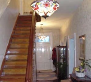 A wooden staircase leading to a door, a chandelier, and a framed picture on the wall.