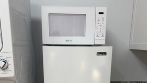 Une cuisine compacte équipée d’un four à micro-ondes, d’un réfrigérateur et d’un lave-linge.