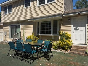 A two-story house with a covered patio, a front door, and a small front yard with a table and chairs. - The Marble Manor by Boardwalk (Myrtle Beach)