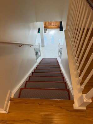 A wooden staircase with white railings and a patterned carpet. - The Marble Manor by Boardwalk (Myrtle Beach)
