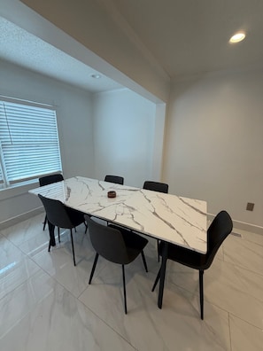 A modern meeting room with a marble table, black chairs, and a large window with blinds. - The Marble Manor by Boardwalk (Myrtle Beach)